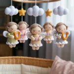 A baby mobile with crocheted angels, stars, and clouds hanging over a wicker bassinet draped with knitted blankets.