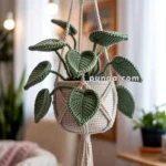 A crocheted plant with green leaves hanging in a macramé holder, suspended over a marble table in a cozy, softly lit room.