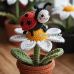 A crocheted ladybug sits on top of a crocheted daisy, with a yellow center and white petals, placed in a crocheted brown pot on a wooden surface.