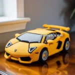 A crocheted model of a yellow sports car, resembling a Lamborghini, placed on a wooden table near a window.