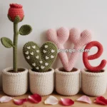 A display of crochet decor spelling the word "love" in individual pots: a red rose, a green heart with white hearts, two pink hearts forming the letter V, and a red letter E.