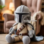 A crocheted doll dressed in a space warrior outfit, including a helmet and a cape, sitting on a wooden table with a cozy room in the background.