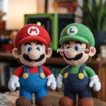 Two crochet dolls resembling iconic video game characters, one dressed in red with an 'M' on the cap and the other in green with an 'L', standing on a wooden table.
