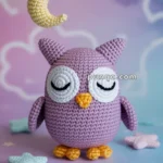 A crochet purple owl with closed eyes and yellow beak and feet, set against a colorful background with stars and a crescent moon hanging above.
