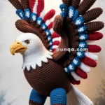 A crocheted eagle with red, white, and blue wings and brown feathers, sitting on a wooden platform under a warm light.