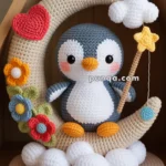 A crocheted penguin sits on a crescent moon surrounded by colorful flowers, a red heart, and puffy clouds, holding a wand with a star.