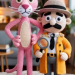 Crocheted figures of a pink panther and a detective with a magnifying glass, dressed in a yellow coat and hat, standing on a black mat with pink dots, in a cozy room setting.