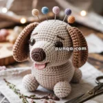A handmade crochet dog pin cushion with colorful pins inserted into its back sits on an embroidered fabric, next to a pair of scissors on a wooden surface.