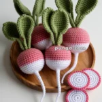 Crocheted radishes with green leaves and pink tops in a wooden bowl, alongside crocheted radish slices.