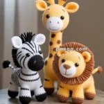 Three crocheted animals, a zebra, giraffe, and lion, are placed on a wooden table against a softly lit background.