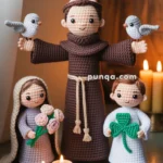 Three crocheted figures, including a monk with birds on his shoulders, a woman holding roses, and a child holding a clover, are displayed on a table with lit candles and prayer cards.