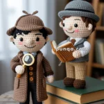 Two crocheted dolls on a wooden table, one dressed as a detective with a magnifying glass and the other with a book, standing on stacked books.