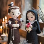 Two hand-crocheted dolls in religious attire, one holding a cross with birds on the shoulders, and the other holding a bouquet of pink roses, are displayed on a table surrounded by candles and lavender sprigs.