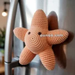 A knitted starfish toy attached to a stainless steel refrigerator door.