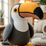 A crocheted toucan toy with a large yellow and black beak sits on a wooden table in a cozy room.