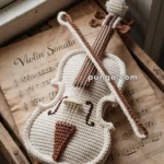 A crocheted violin and bow placed on top of a sheet of music labeled "Violin Sonata."