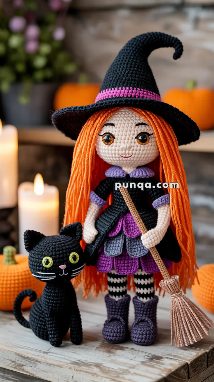 Crocheted doll dressed as a witch with orange hair and a black hat, standing next to a black crocheted cat, surrounded by pumpkins and candles.