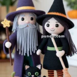 Crocheted figures of a wizard and a witch standing next to a black cat, an orange pumpkin, and each holding a staff and broom respectively, all on a circular mat with a blurred background.