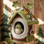 A crocheted birdhouse hanging from a branch, adorned with colorful flowers and leaves, featuring a small crocheted bird peeking from the entrance.