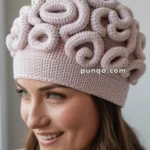 A woman wearing a unique hat designed to resemble a brain made from soft, pink yarn.
