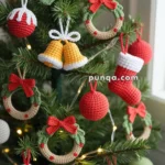 Christmas tree decorated with crocheted ornaments including wreaths, stockings, bells, and baubles in red, green, and white.