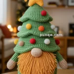 A crochet gnome designed like a Christmas tree, adorned with a yellow star on top and colorful balls, standing on a wooden table in a cozy room.
