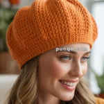 A person wearing a knitted orange pumpkin-shaped hat with a green stem.