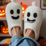 Person wearing knitted white slippers shaped like smiling ghosts with black eyes and mouths, sitting on a couch with a festive Halloween background of jack-o'-lanterns and bat decorations.