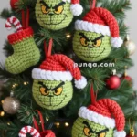 Crocheted Christmas tree ornaments featuring green faces with red Santa hats and expressive eyes, along with green stockings with candy canes, hanging on a decorated tree.
