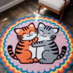 Circular crochet rug featuring two cartoon cats hugging, with one orange and the other gray, against a colorful, scalloped edge design on a wooden floor beside a white armchair.