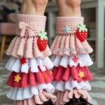 Person wearing colorful crochet leg warmers with strawberry and bow decorations, paired with black platform shoes.