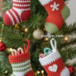 Four crochet Christmas stockings in red, white, and green, each filled with candy canes, hanging on a decorated Christmas tree.