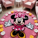 A pink living room with two pink armchairs and a round rug featuring a cartoon mouse character wearing a pink polka-dot dress and bow, surrounded by crocheted flowers and hearts.